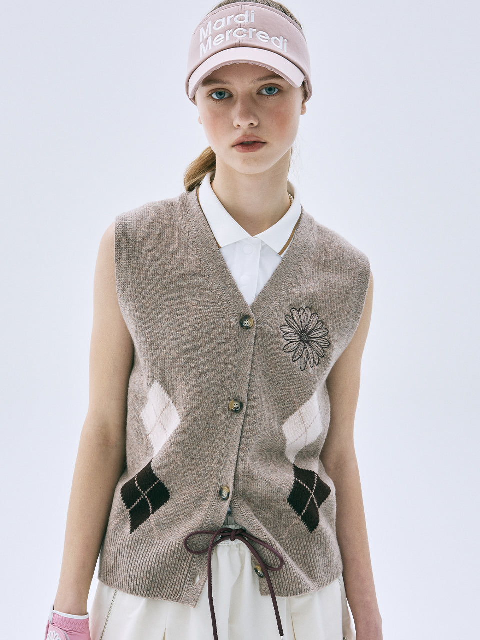 Woman wearing a patterned vest and visor with a plain background