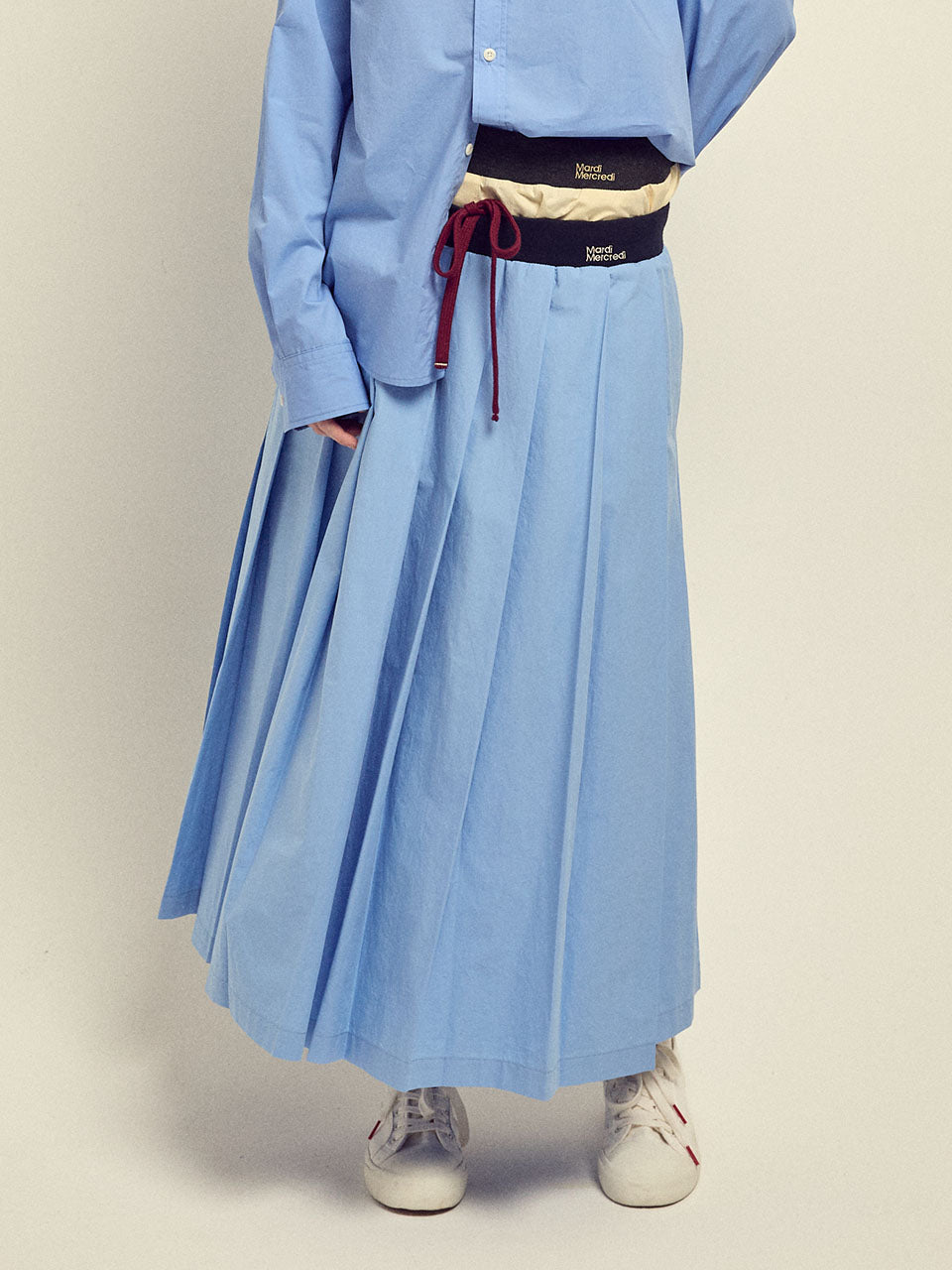 Person wearing a light blue outfit with a skirt and shirt on a plain background