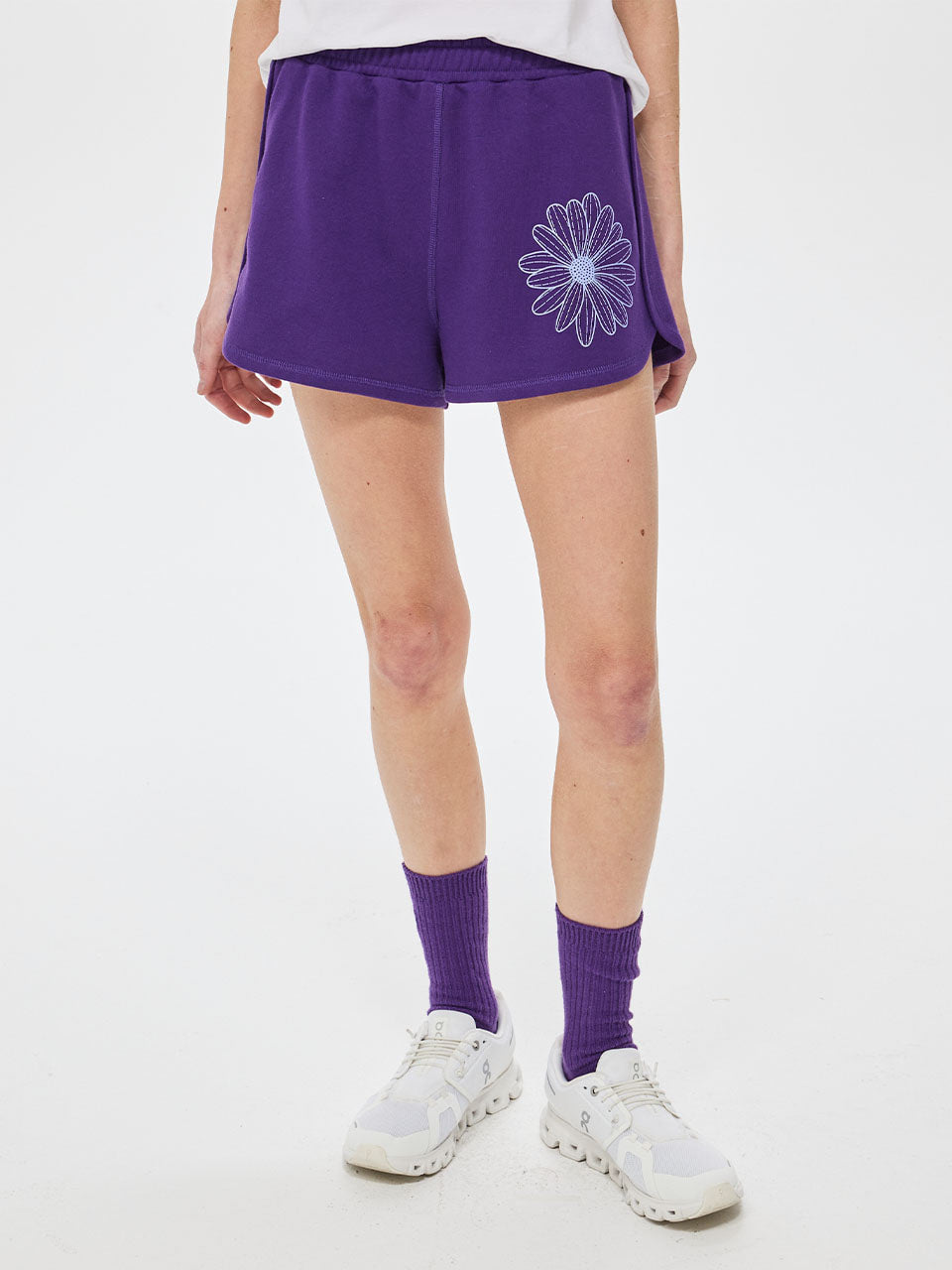 Person wearing purple shorts with a floral design on a white background