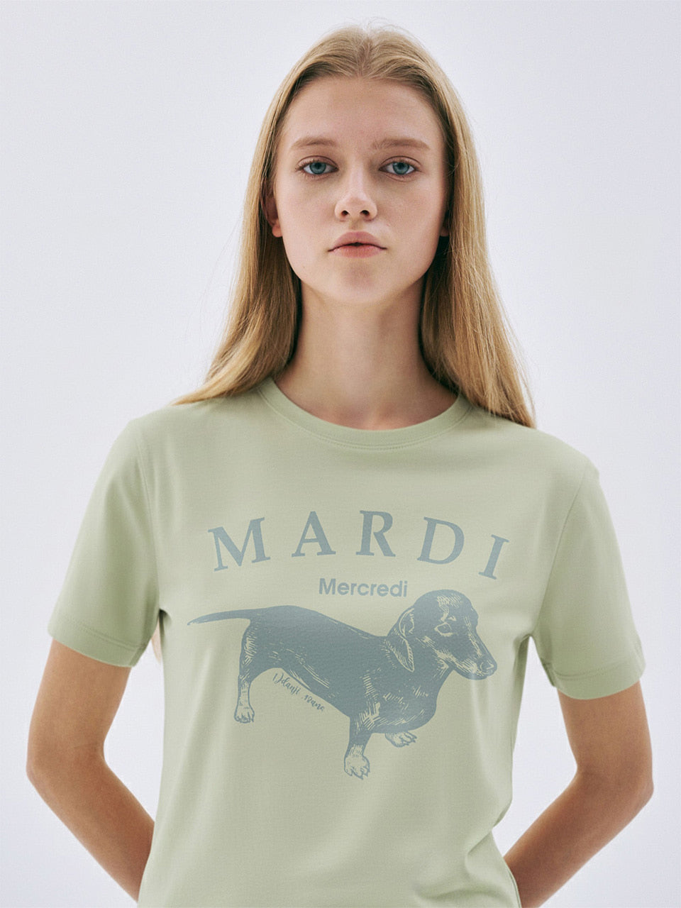 Person wearing a light green t-shirt with 'Mardi' and a dachshund graphic on a white background