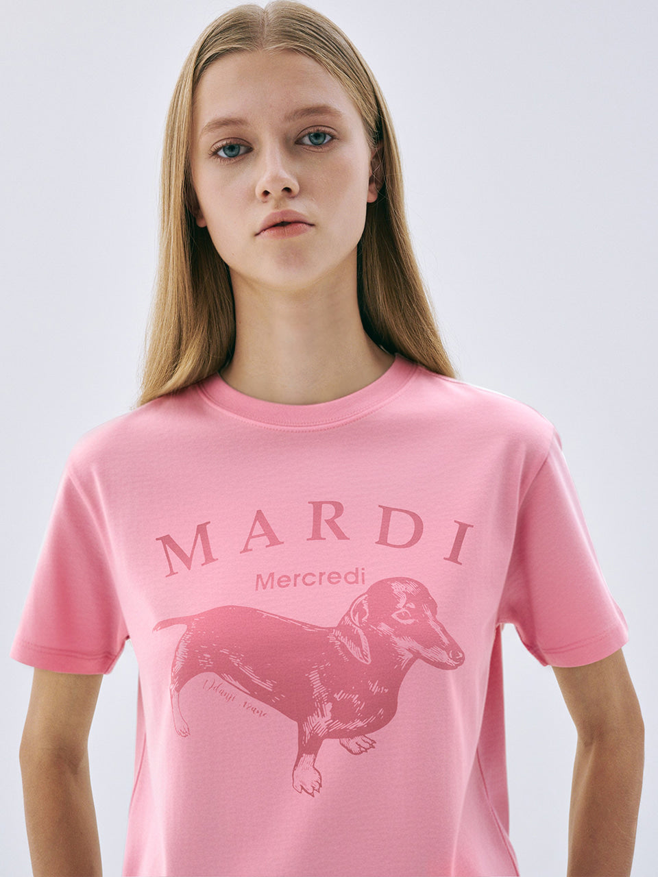 Young girl wearing a pink t-shirt with 'Mardi' and a dachshund graphic on a light gray background