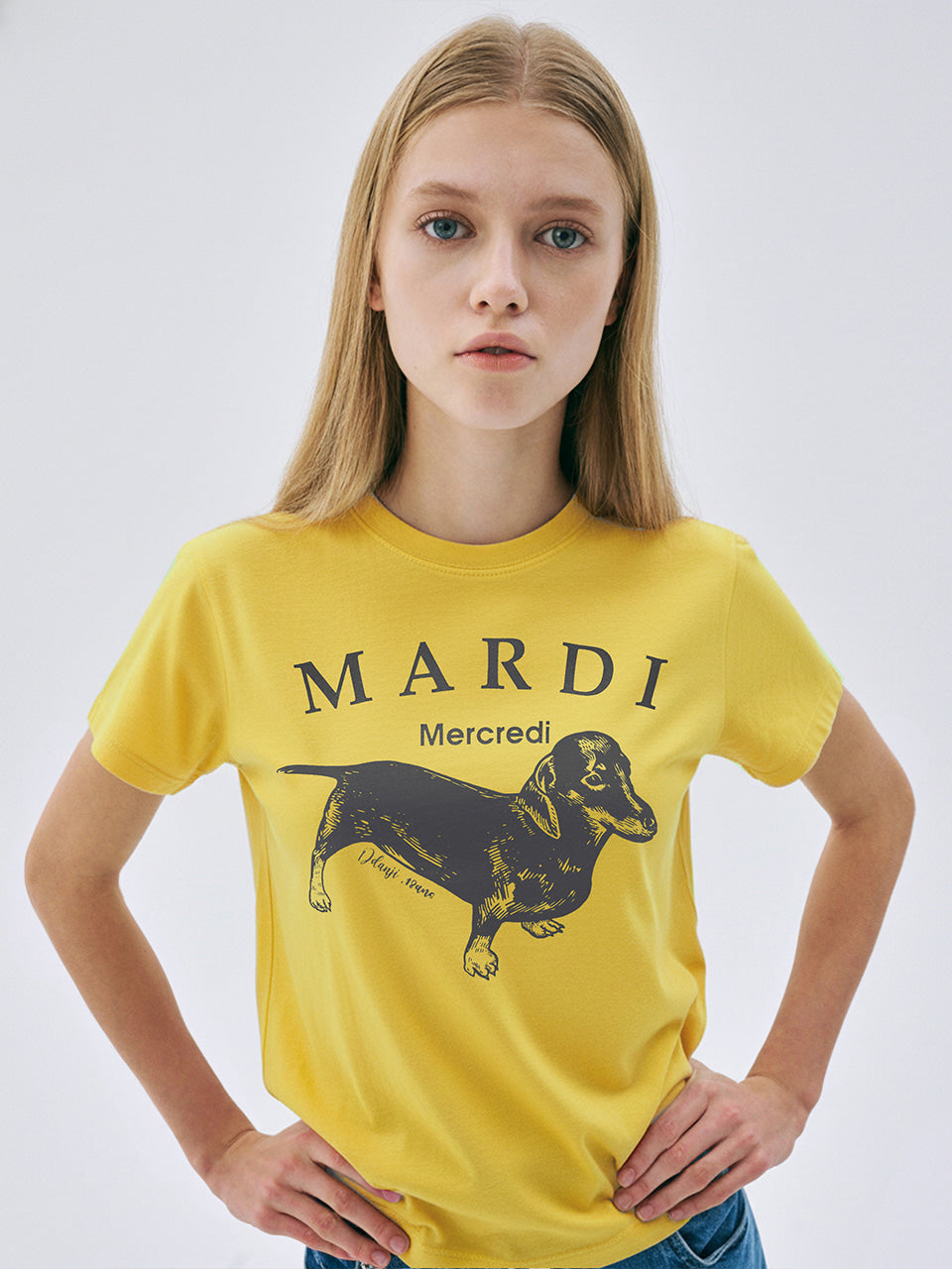 Person wearing a yellow t-shirt with 'Mardi' and a dachshund graphic on a white background