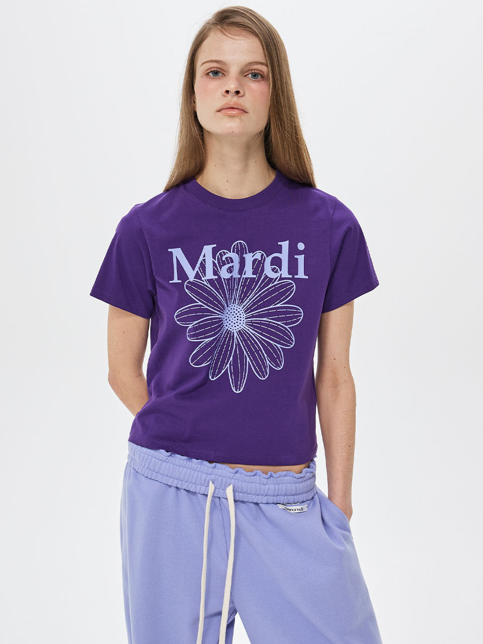 Person wearing a purple t-shirt with 'Mardi' and a flower design on a white background