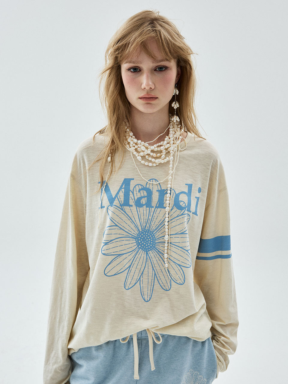 Woman wearing a beige sweatshirt with a blue flower design and 'Mandi' text on a white background