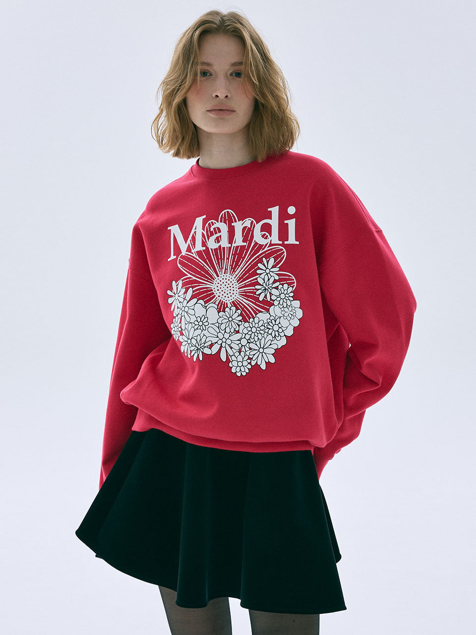 Person wearing a red sweatshirt with 'Mardi' and floral design on a white background