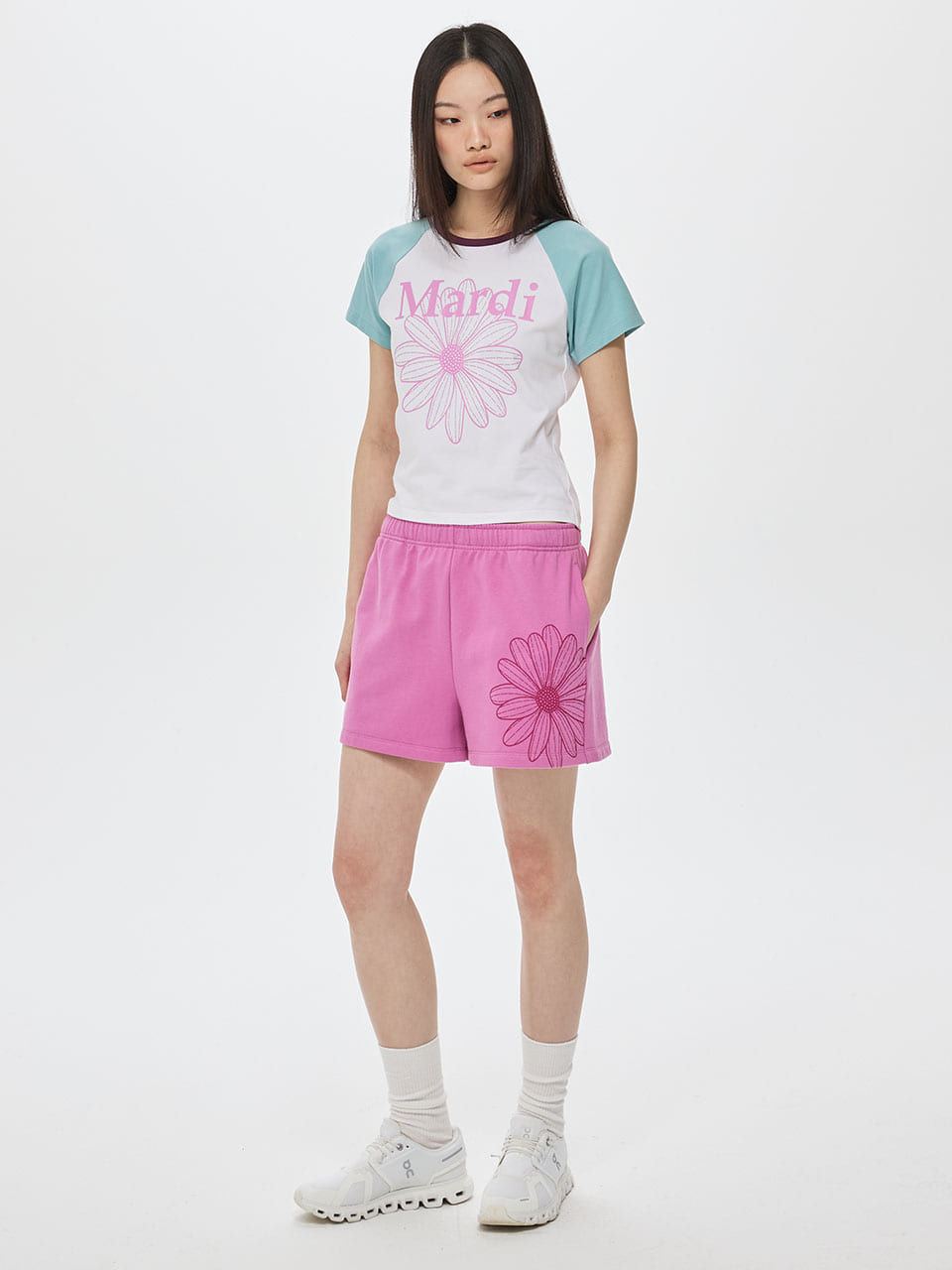 Person wearing a white and blue top with pink shorts on a white background