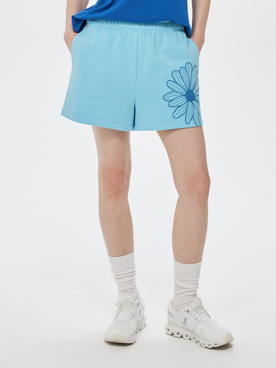 Person wearing a light blue skirt with a floral design on a white background