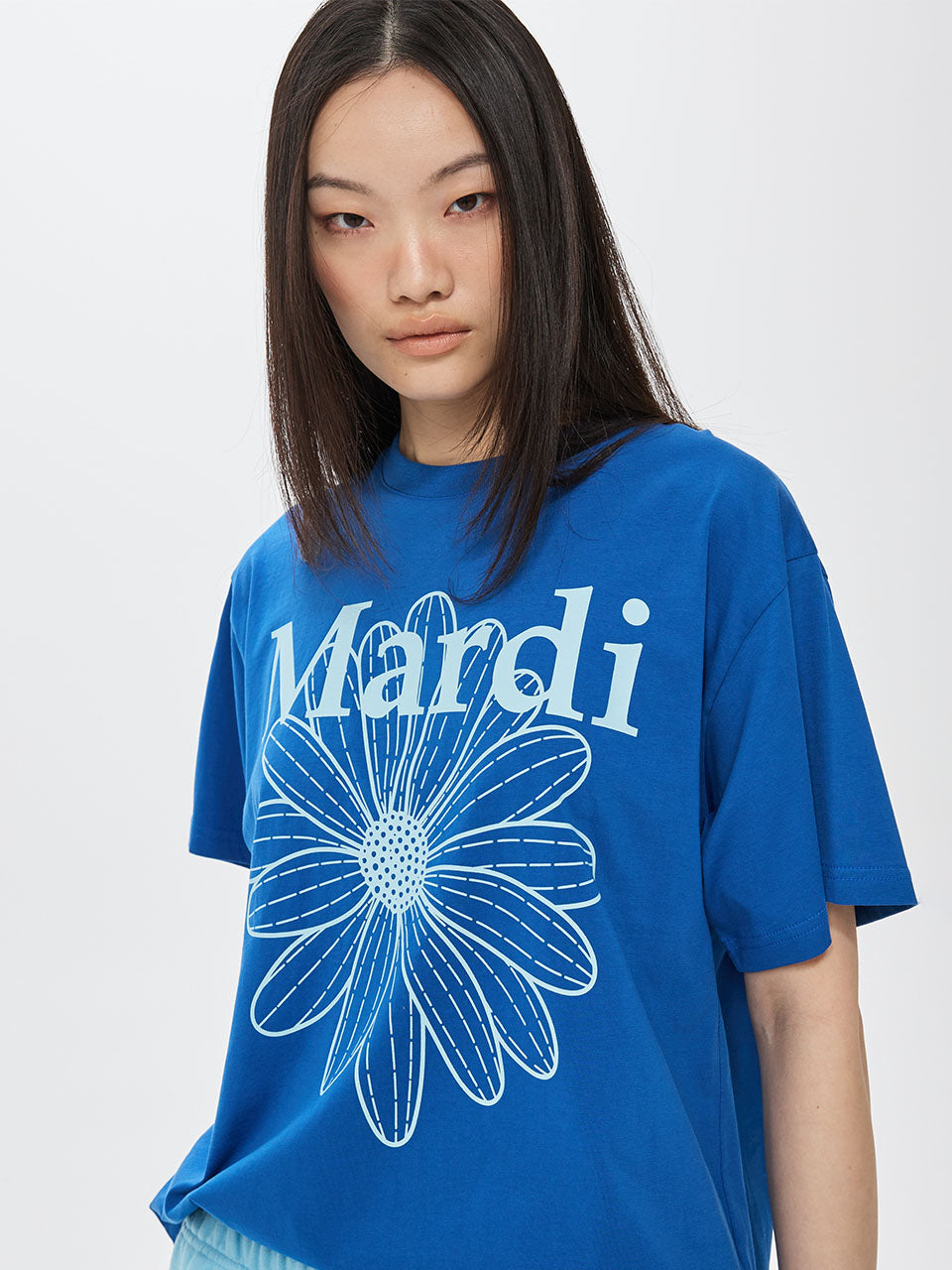 Person wearing a blue t-shirt with 'Mardi' and a flower design on a white background