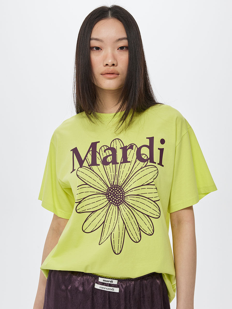 Person wearing a bright green t-shirt with a flower graphic and 'Mardi' text on a white background