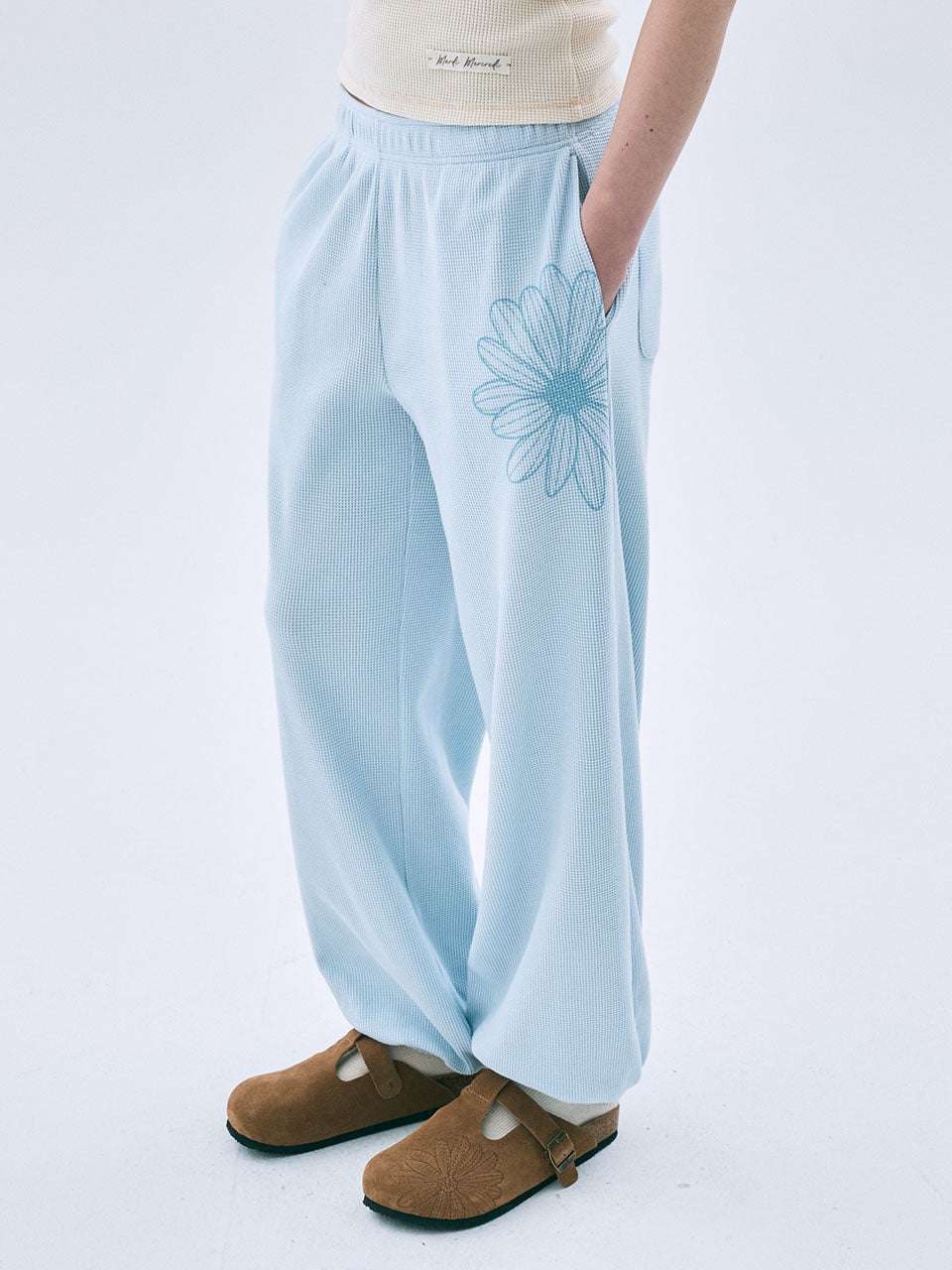 Light blue pants with a floral design worn by a person on a white background