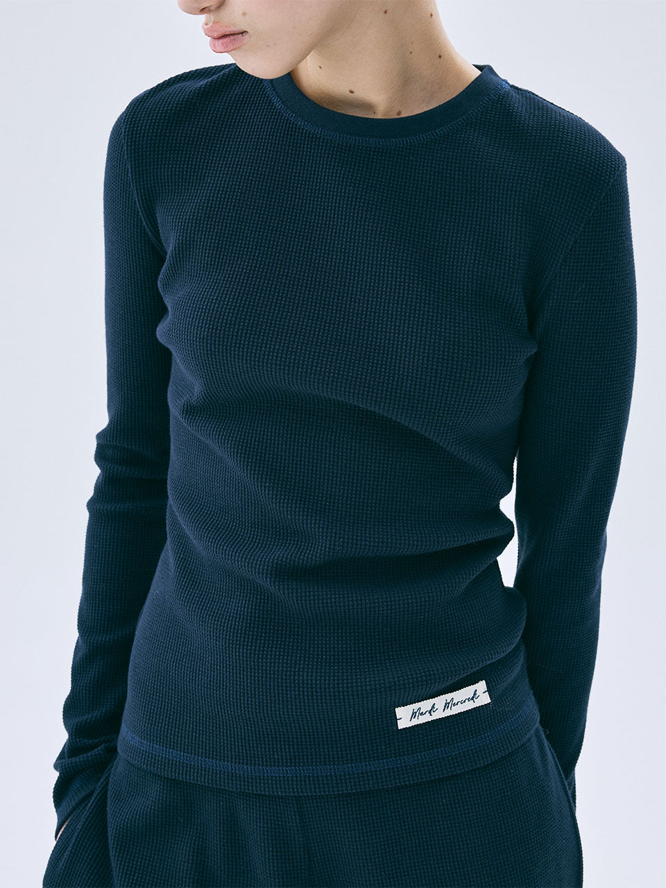 Navy blue long-sleeve top with a brand label on a white background