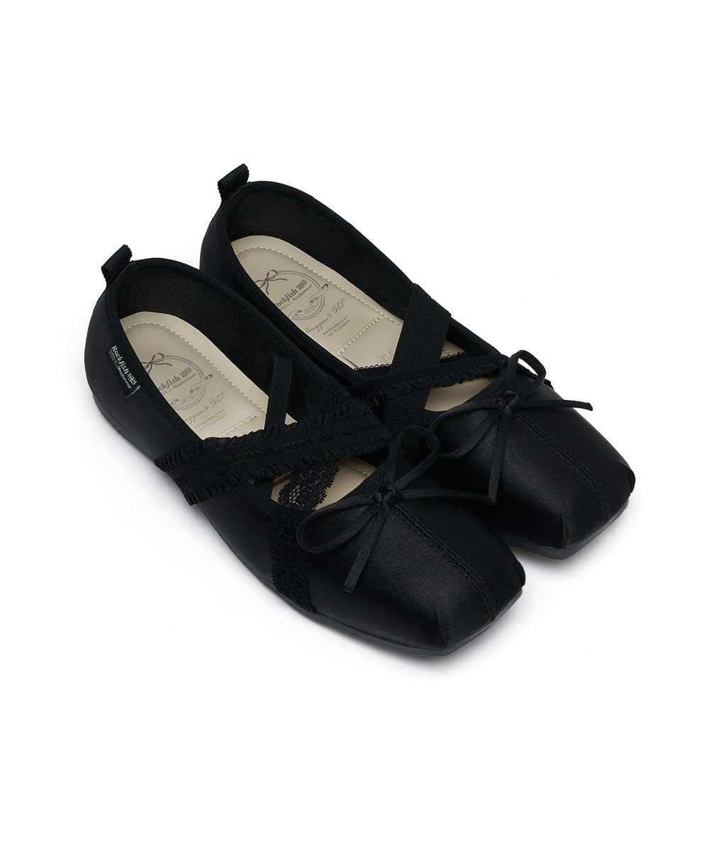 Pair of black ballet flats with ribbons on a white background