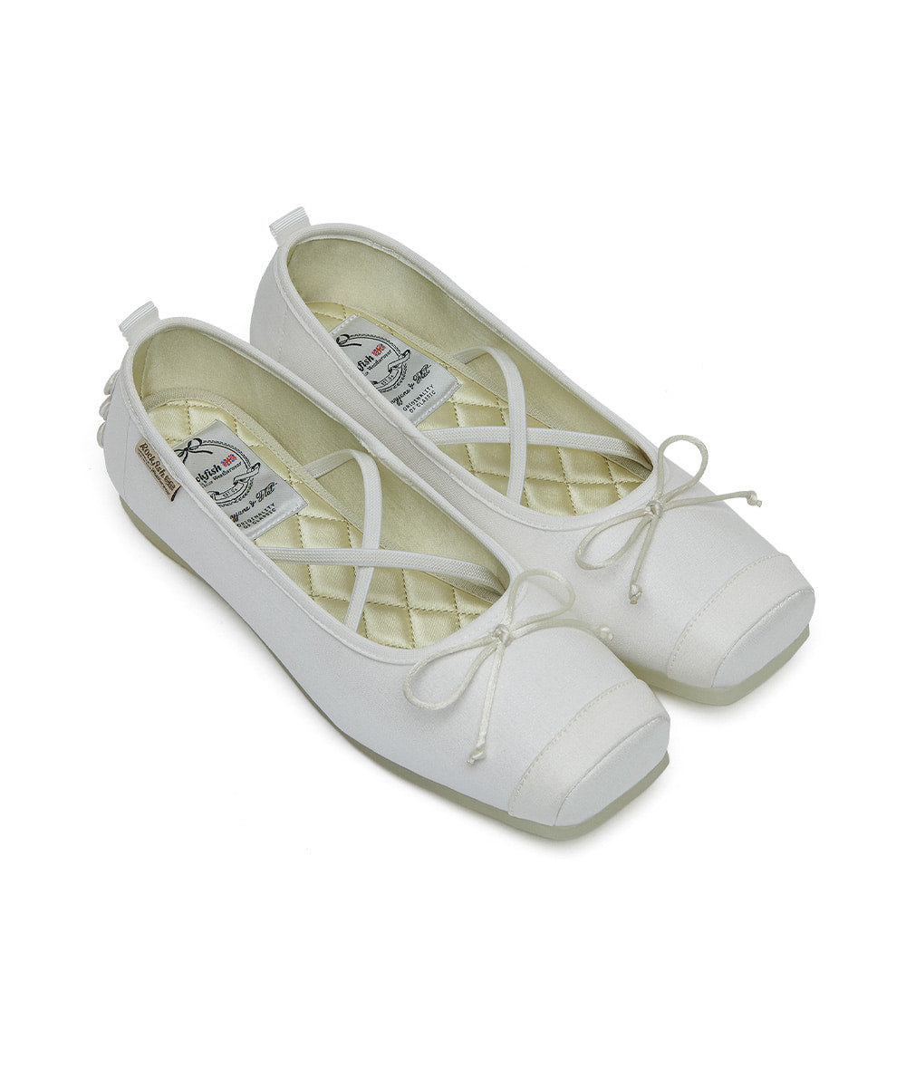White ballet flats with bow detail on a white background