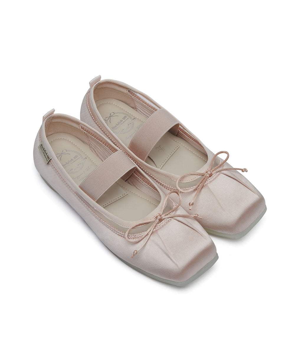 Pair of light pink shoes with bow details on a white background