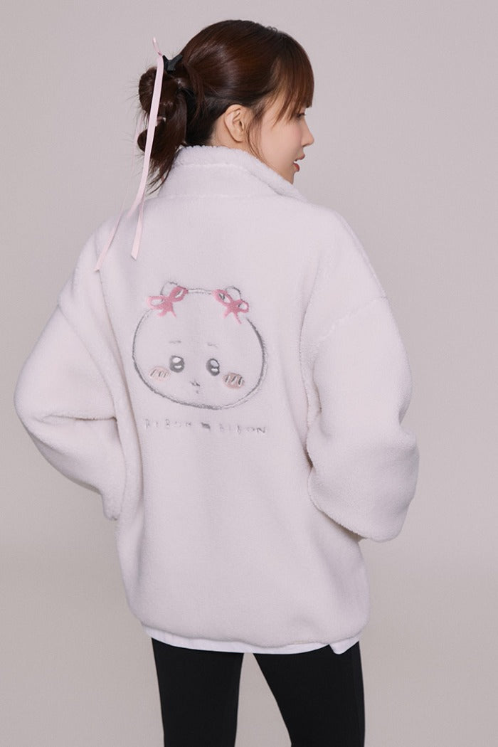 Person wearing a light gray hoodie with a cartoon design on the back against a plain background