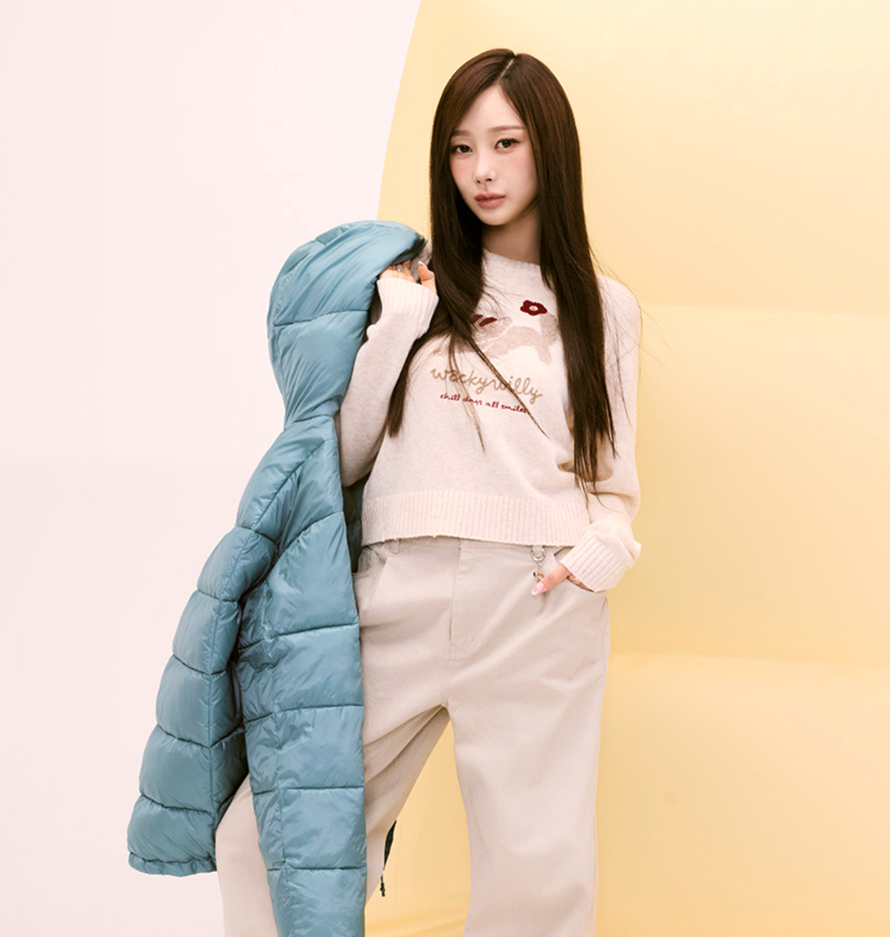 Gisele holding a blue puffer jacket against a gradient background